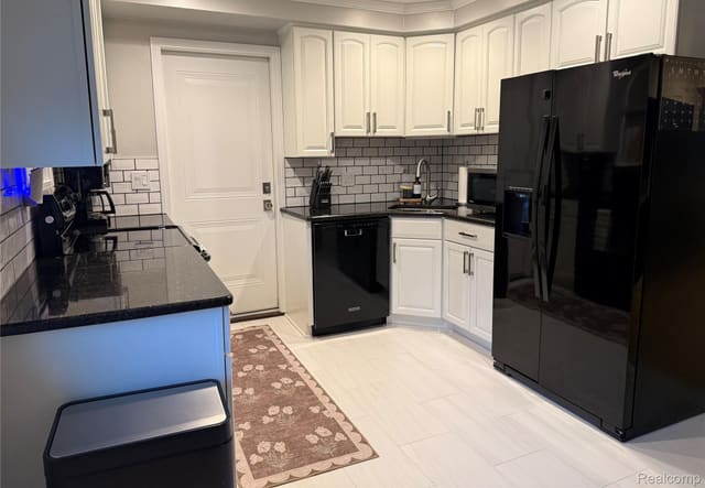 Kitchen with subway-tile backsplash and black refrigerator
