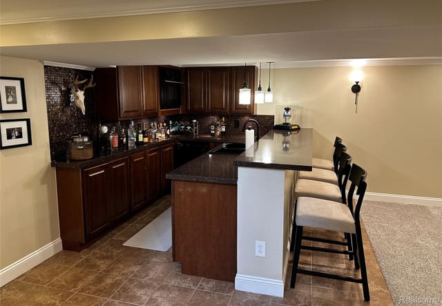 Finished-basement wet bar with custom cabinetry and counter seating