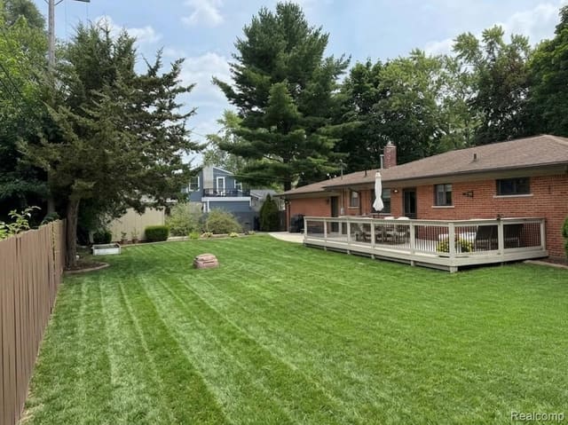 Large fenced backyard with open lawn behind the ranch